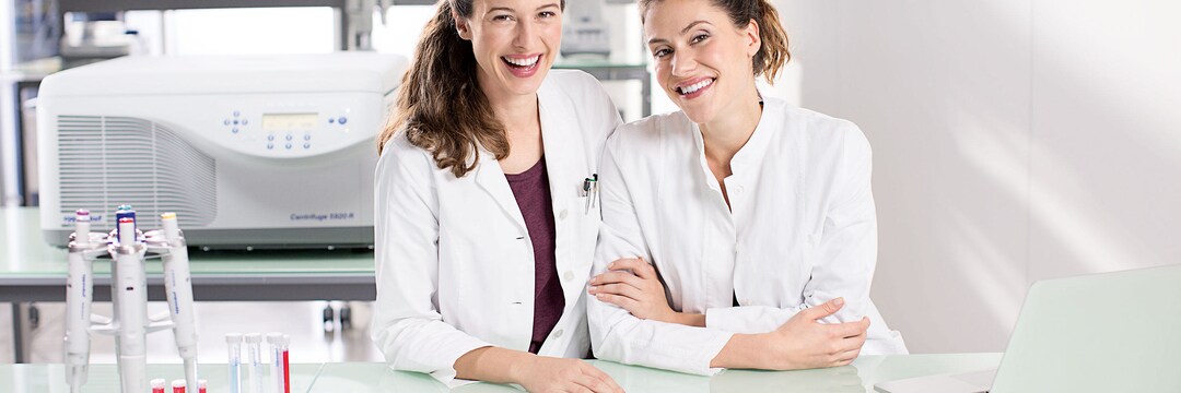 Two women leaning with their upper body against the laboratory table with the Centrifuge 5920 R in the background