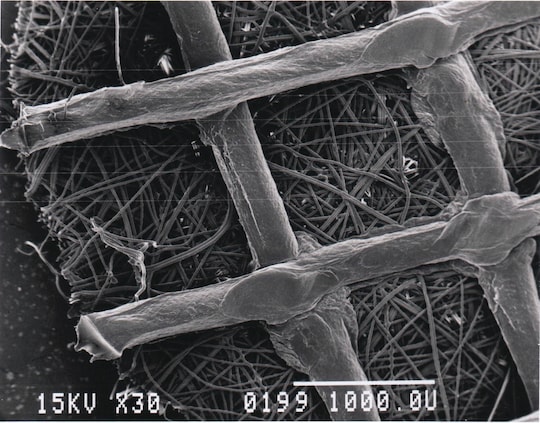High-resolution micrograph of a Fibra‑Cel disk indicating the polyester mesh with polypropylene support