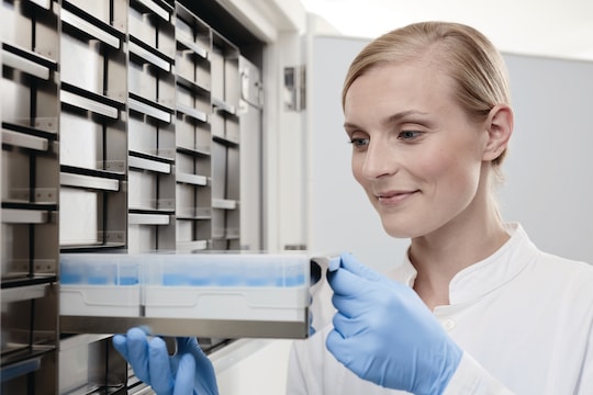 Female scientist pulls out a freezer rack filled with samples out of ULT freezer