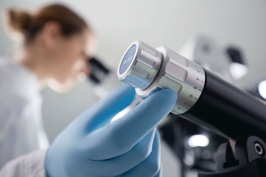 Ergonomic cell manipulation Person handling microinjectors and other microscale equipment used in cell manipulation, while working with the microscope.