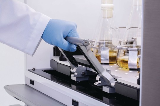 Comfortable access to sample flasks Scientist pulls out a shaker platform with heavy sample flasks, supported by an ergonomic design.