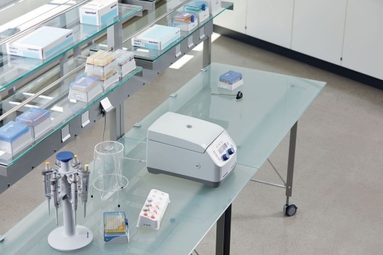 PhysioCare Concept® - Centrifuges A benchtop centrifuge next to a pipette carousel in an ergonomically designed laboratory.