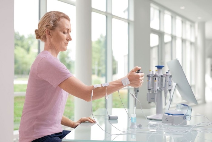 Comfortable handle for your pipette carousel. A scientist sits at the bench and is connected with electrodes at the arm to test muscle tension while using an Eppendorf pipette.