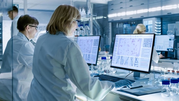 Couple of scientists in front of their computers using lab managemen software