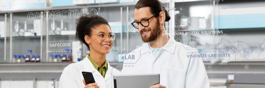 Female scientist in digital lab is holding a smartphone in der hand while male scientist in digital lab is holding a tablet in his hand.