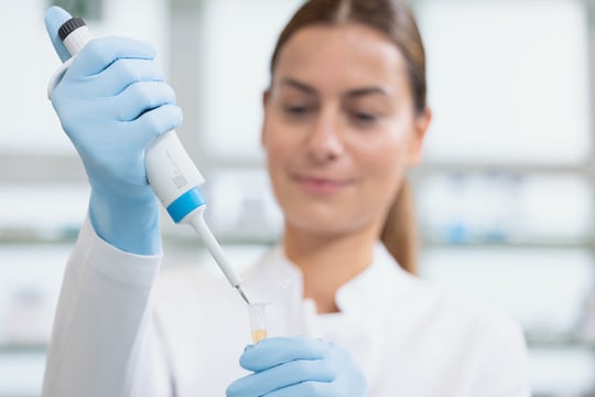 Close-up of a young female scientist pipetting with an Eppendorf Research® 3 neo single-channel pipette, 0.1-2.5 µL, dark gray