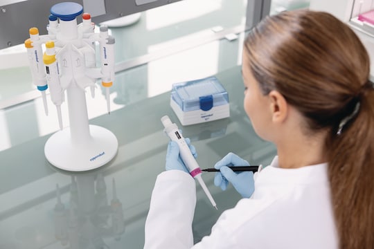 Young female scientist writes on a ColorTag pipette marking ring attached to an Eppendorf Research® 3 neo single-channel pipette