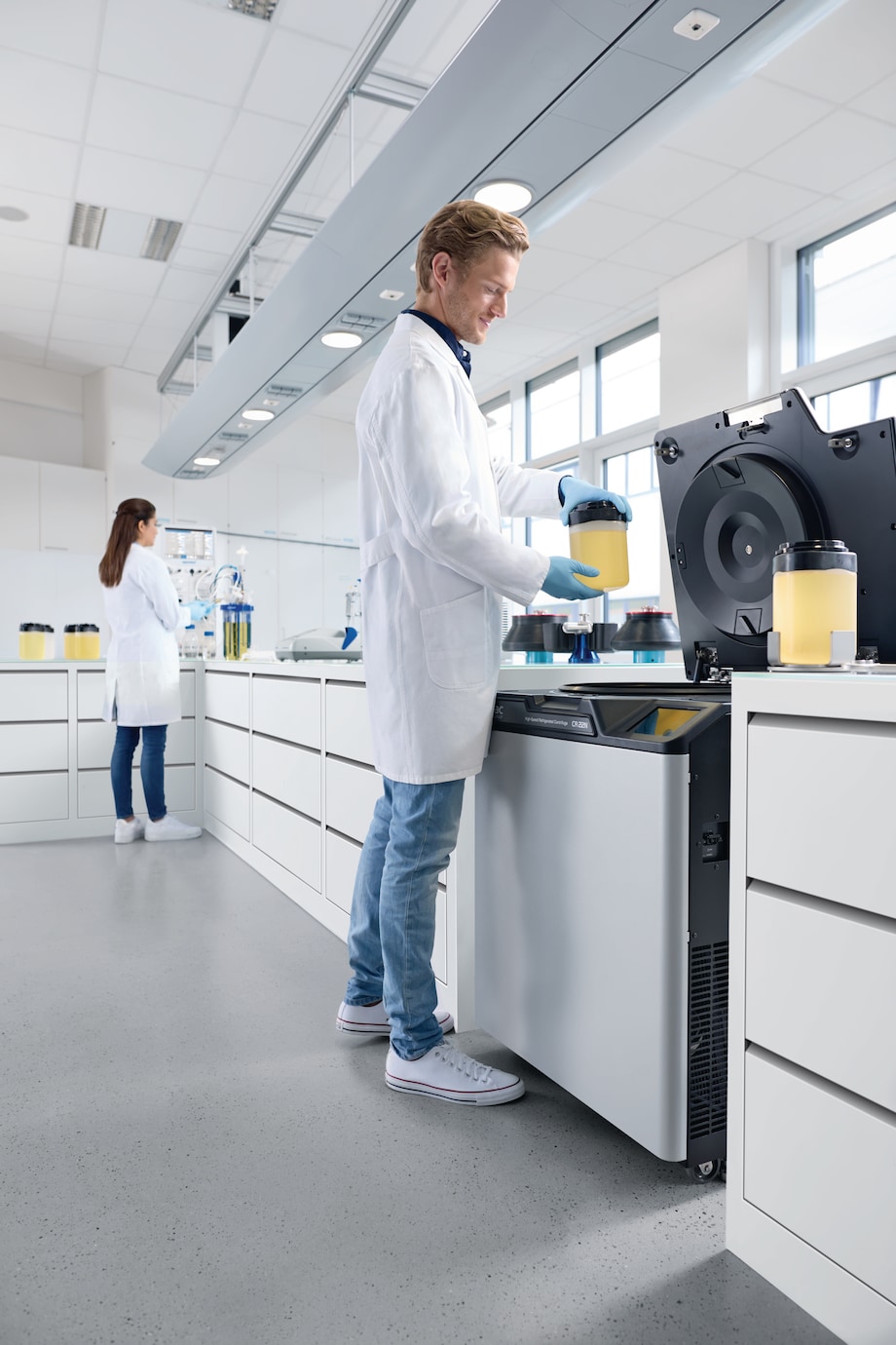 Centrifuge CR22N, man and woman working in lab Man and woman in the lab, inserting bottles in Centrifuge CR22N.