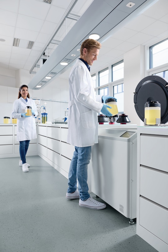 Man and woman in the lab, inserting bottles in Centrifuge CR30NX.