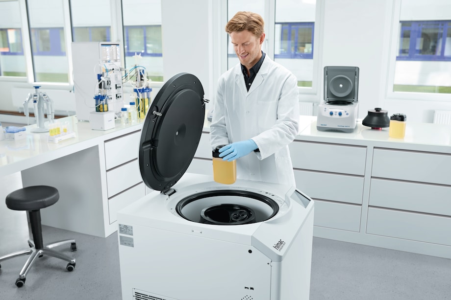 Centrifuge CR30NX, key visual, 1.5 L bottles Man loading 1.5 L centrifuge bottles into the Eppendorf Centrifuge CR30NX