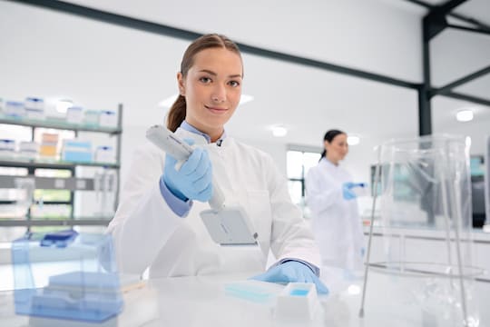 Female Scientist Looking at Camera while using Eppendorf Xplorer® plus 24-channel Pipette to Fill a 384-well Plate