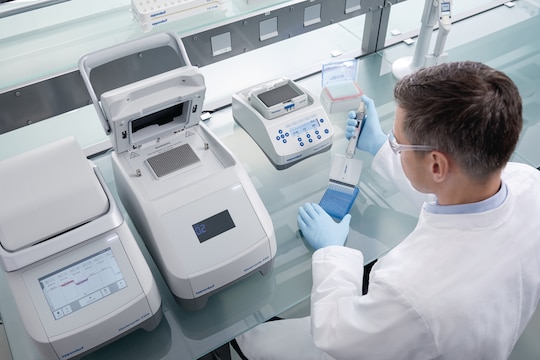 Male laboratory technician works at the bench with PCR, Eppendorf ThermoMixer_REG_ and dispenses liquid in a plate