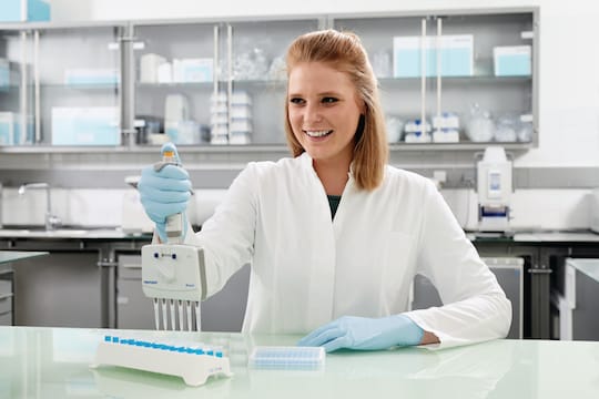 Scientist using a Move It® adjustable tip spacing pipette to transfer liquid from a series of tubes to a plate